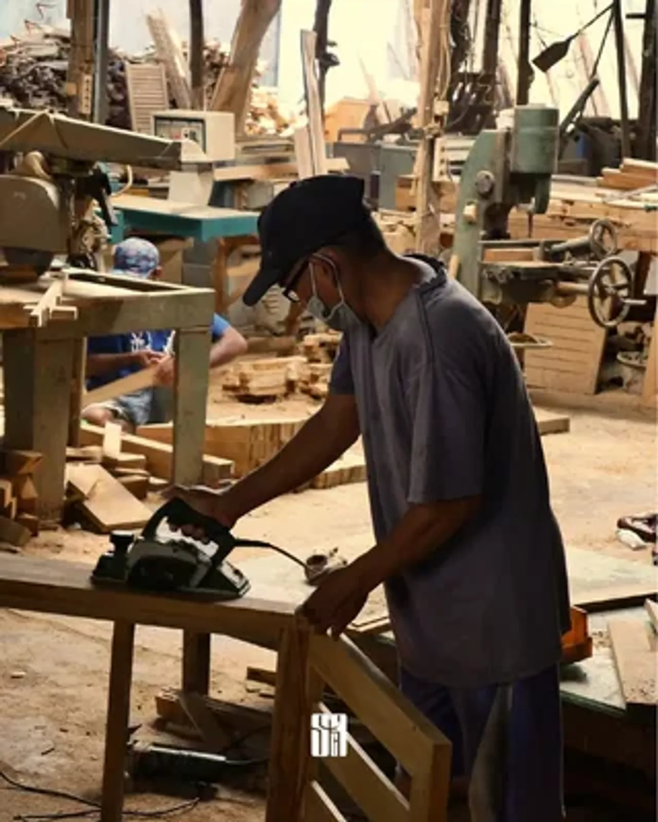 Pekerja menghaluskan kayu di workshop
